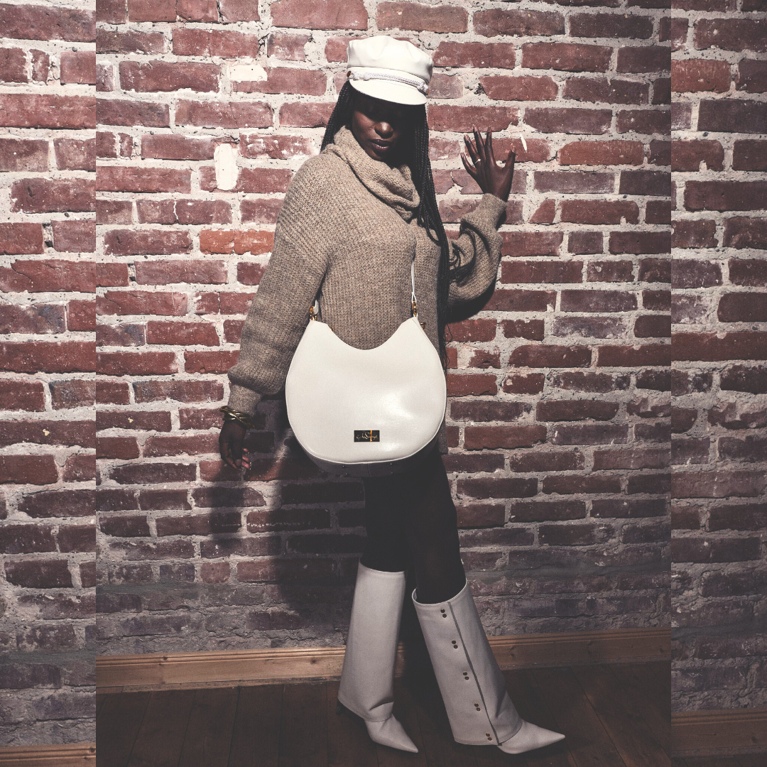 Model mit Ensemble Yve aus Crossbodybag, Bakerboycap und Highschaft Boots in creme