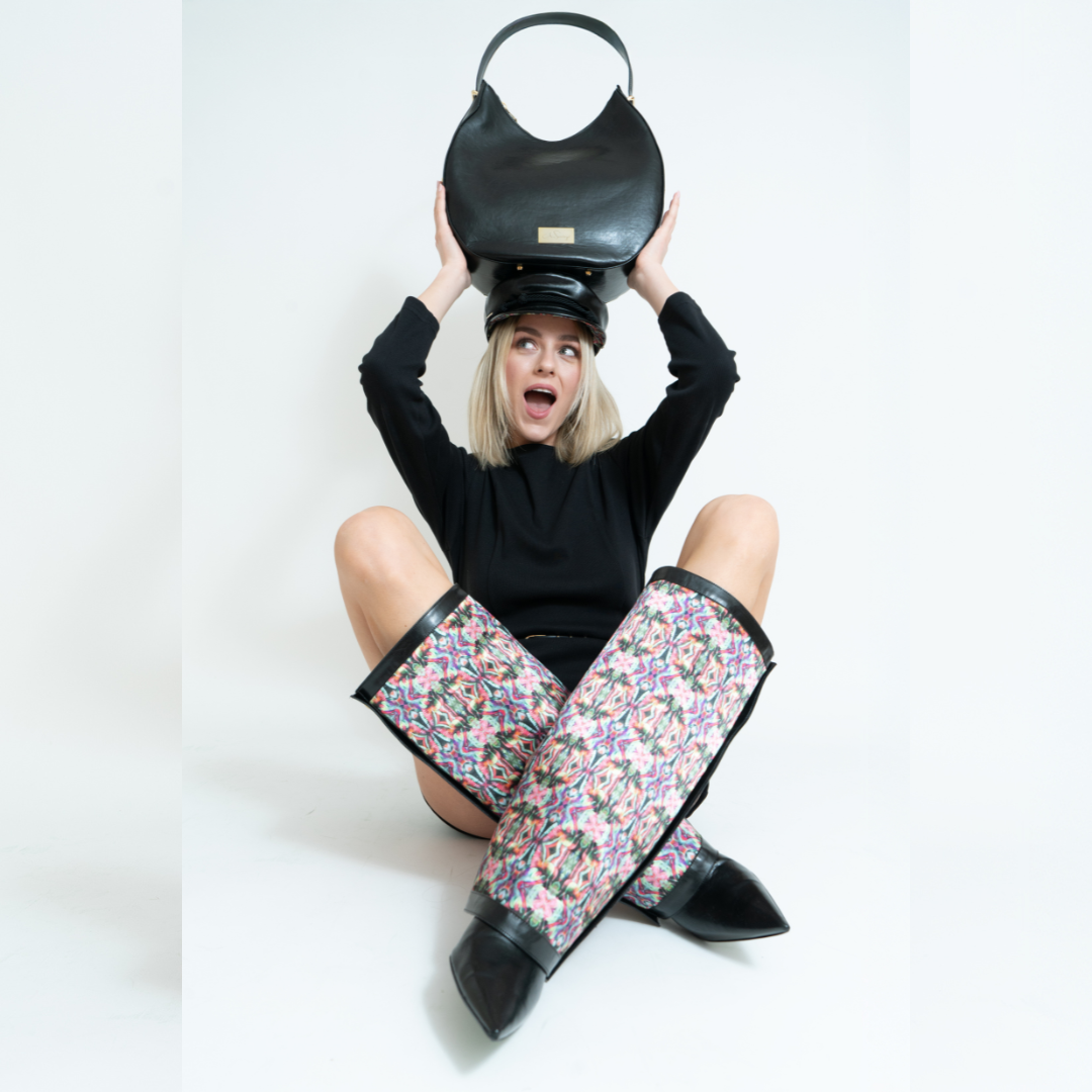 Frau mit Bakerboy Cap Yve und Bag Yve in schwarz sowie Yve Boots in schwarz mit Schaft im Kunst Design