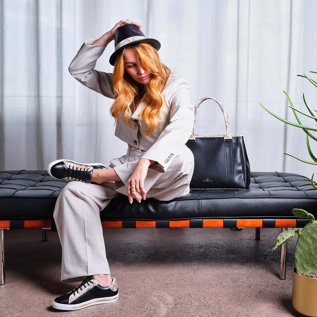 Model mit passender Handtasche, Sneaker und Hut aus veganem Leder in Schwarz und Snake-Optik