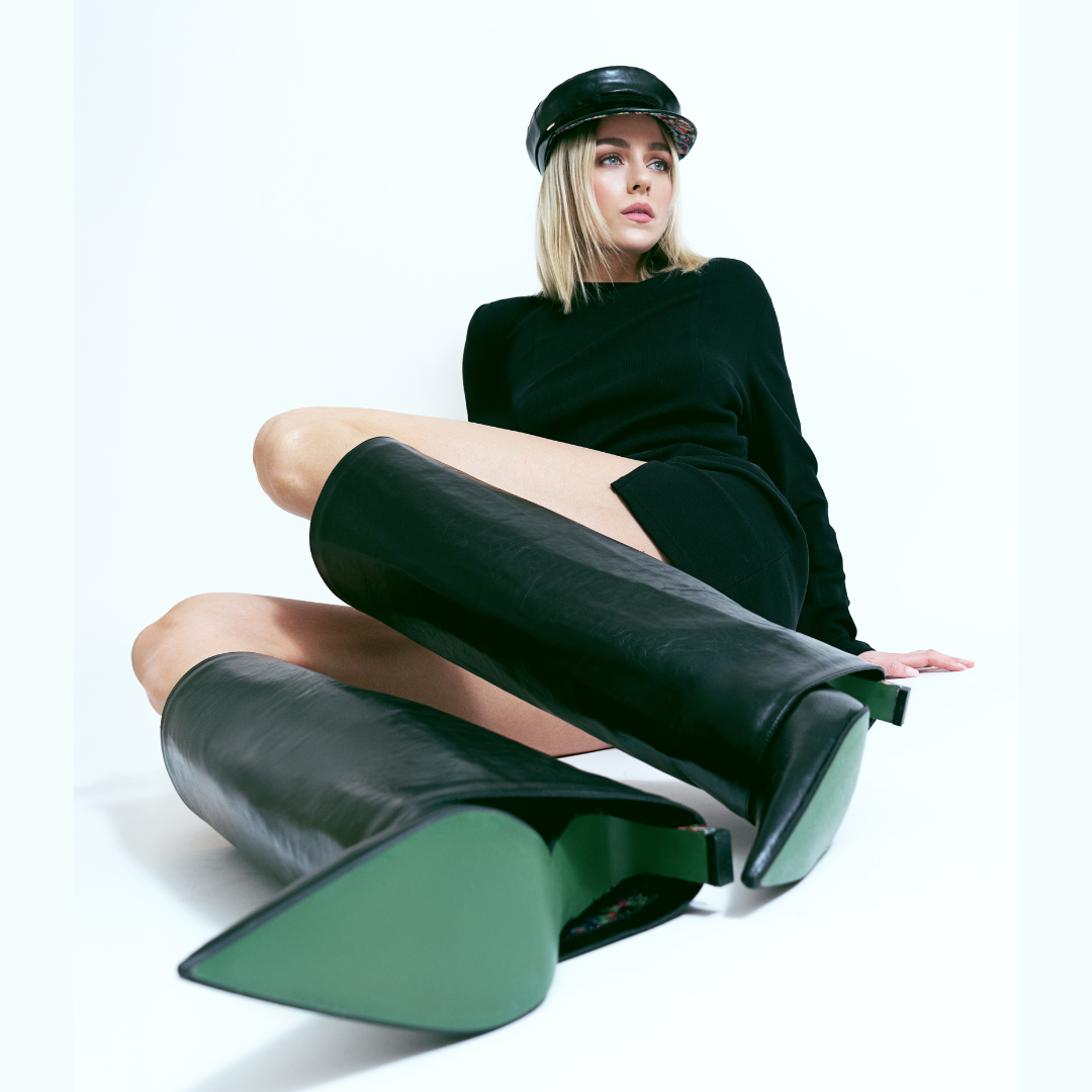 Frau mit Bakerboy Cap Yve in schwarz und Yve Boots in schwarz mit olivfarbener Sohle
