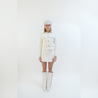 Woman in cream-colored suit with the Yve boots and baker boy cap in cream