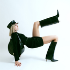 Frau mit dem Ensemble Yve in schwarz aus Handtasche Boots und Bakerboy Cap